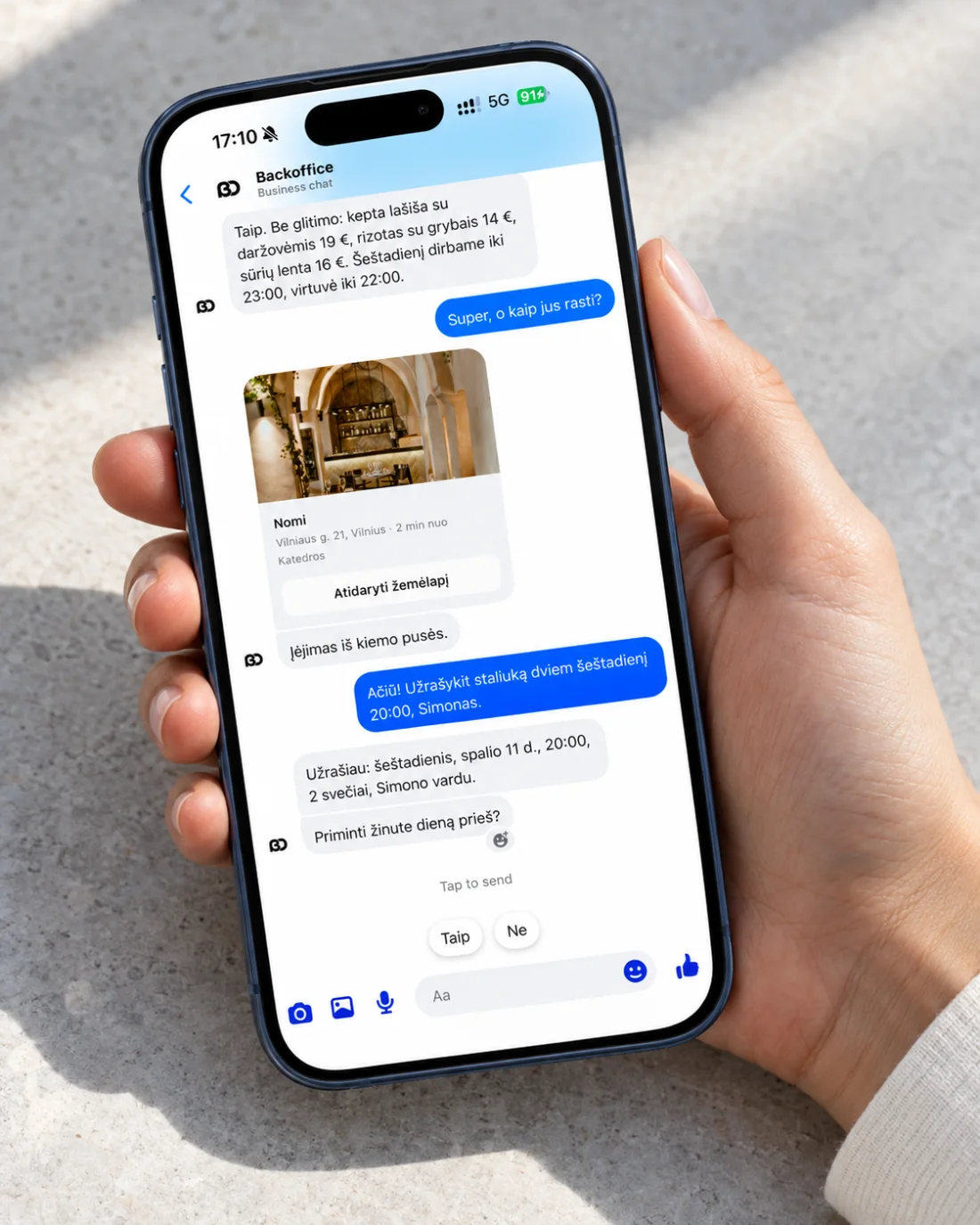 A hand holding a phone with a Messenger chat: dishes with prices and opening hours, a map card with the address and the entrance from the yard, and a table for two booked for Saturday